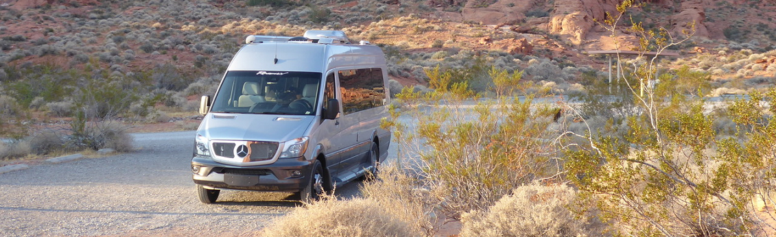 Mercedes Benz RV driving down a gravel road in the desert.